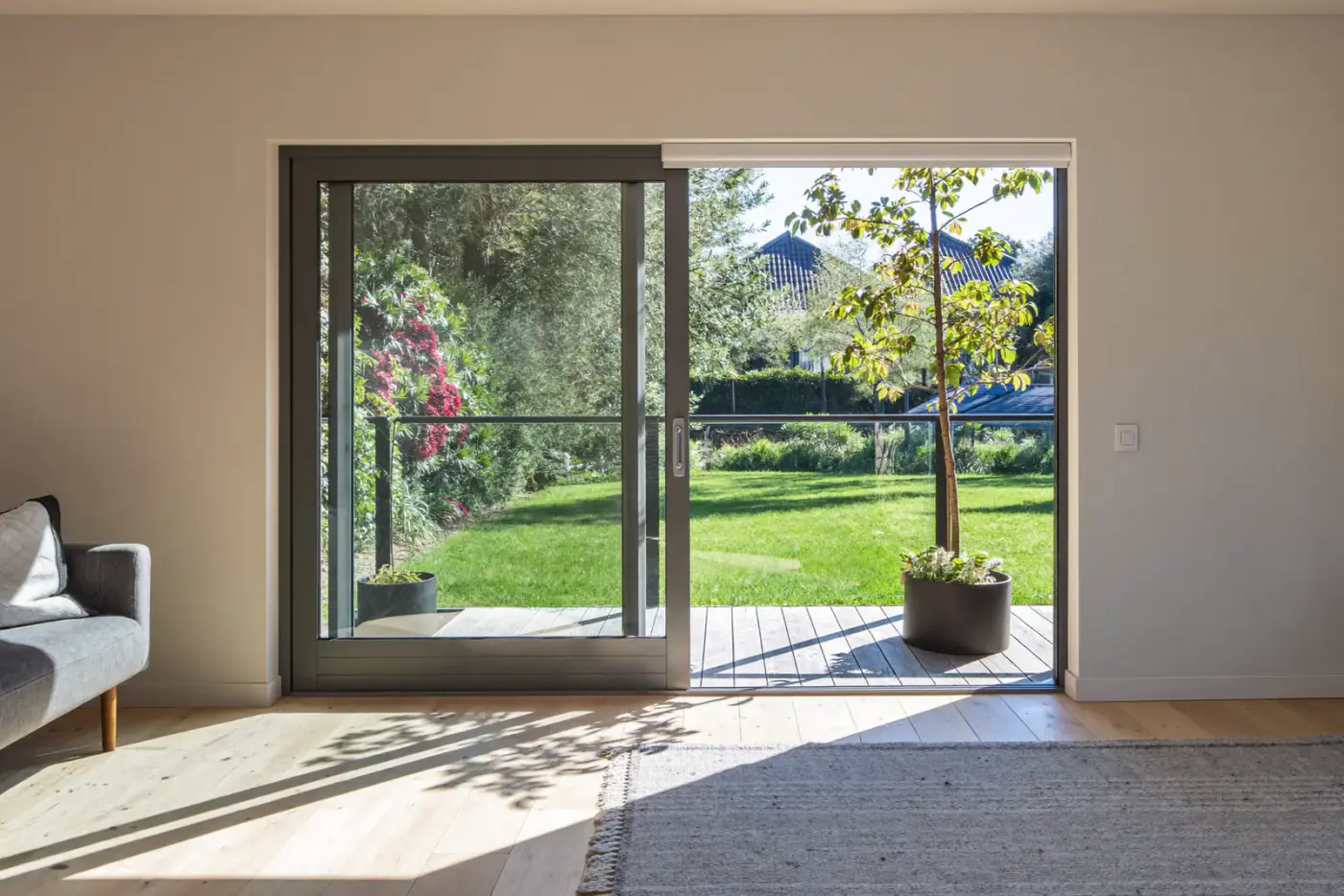 Woonkamer met een brede antraciete aluminium schuifpui naar de tuin