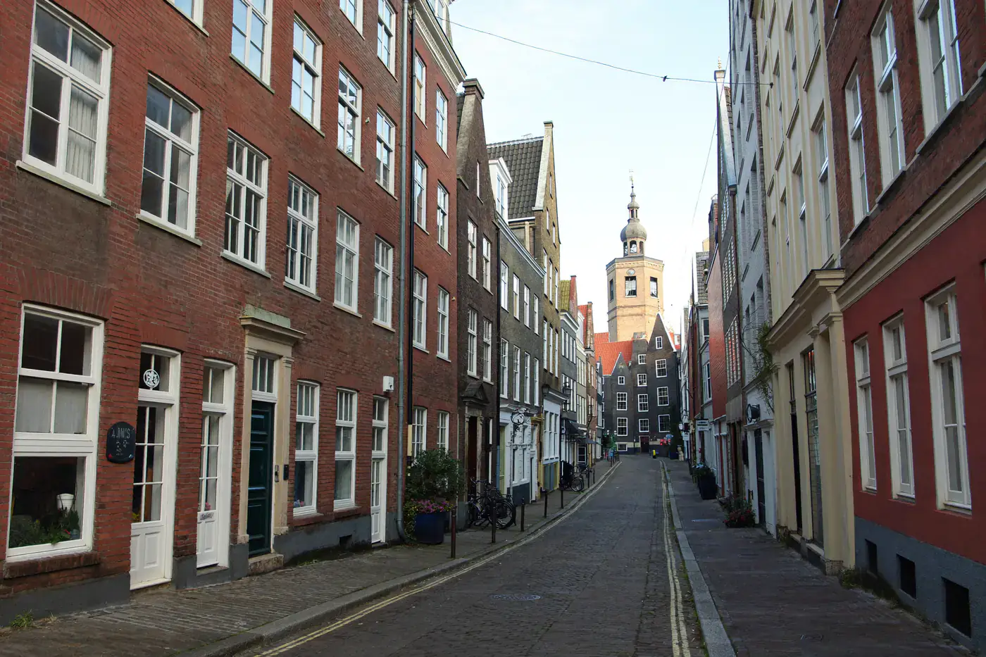 Smalle straat in een oude Nederlandse stad met historische bakstenen gevels en witte houten ramen
