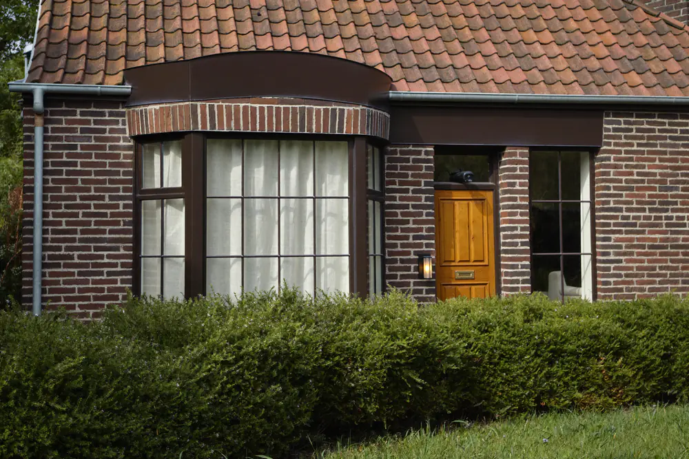 Huis uit de jaren dertig met een erker en originele houten ramen met glas-in-lood bovenlicht