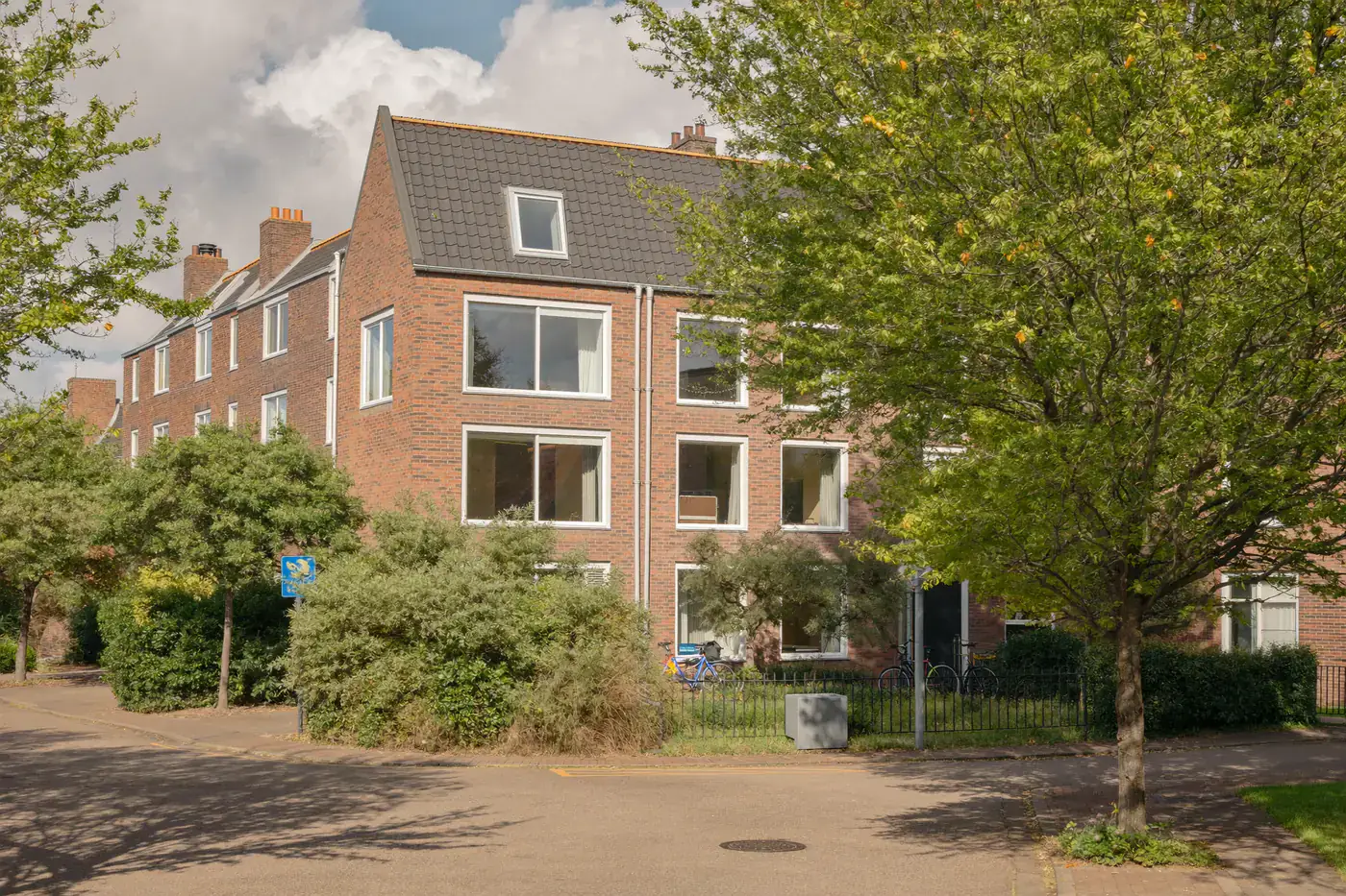 Rustige straat met bakstenen woningen met witte kozijnen en bomen langs de weg