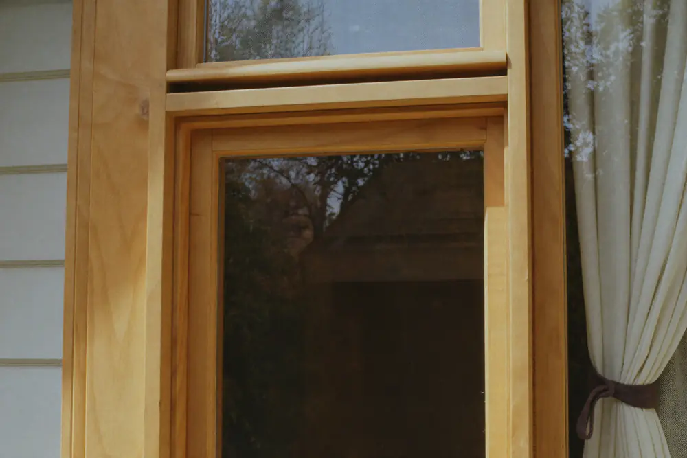 Houten kozijn in gebroken wit in een huis uit de jaren dertig, met zichtbare houtnerf in de hoek