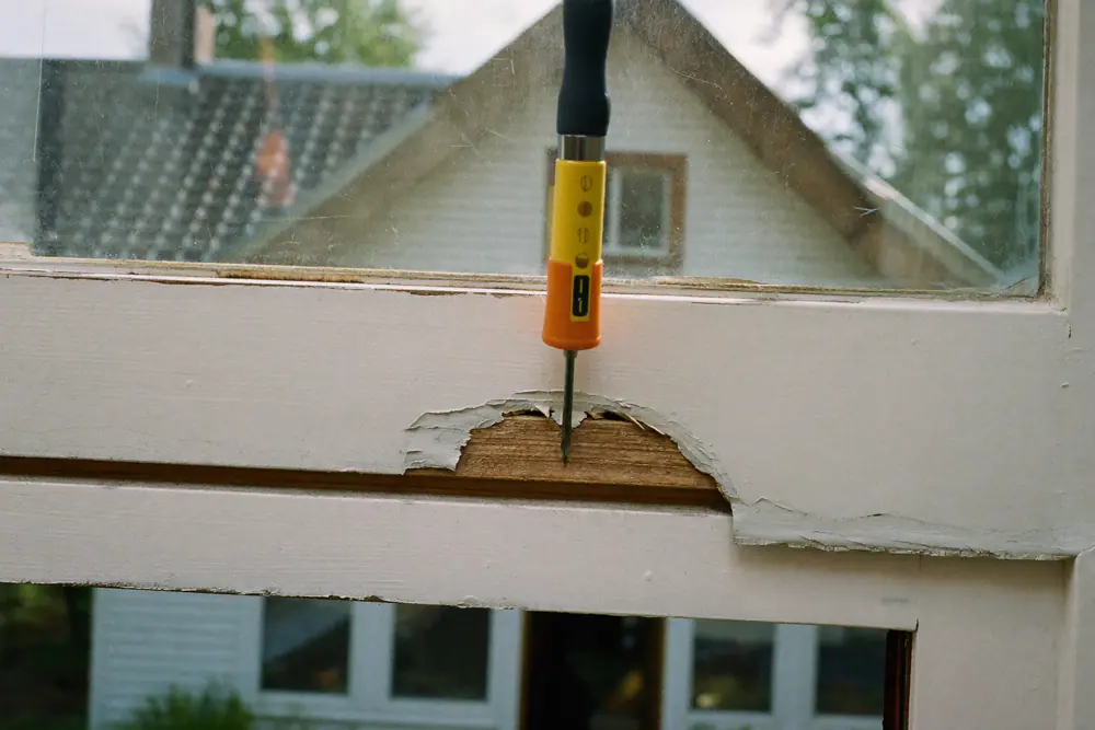 Verrotte onderhoek van een oud houten kozijn met schilfers verf en zacht hout