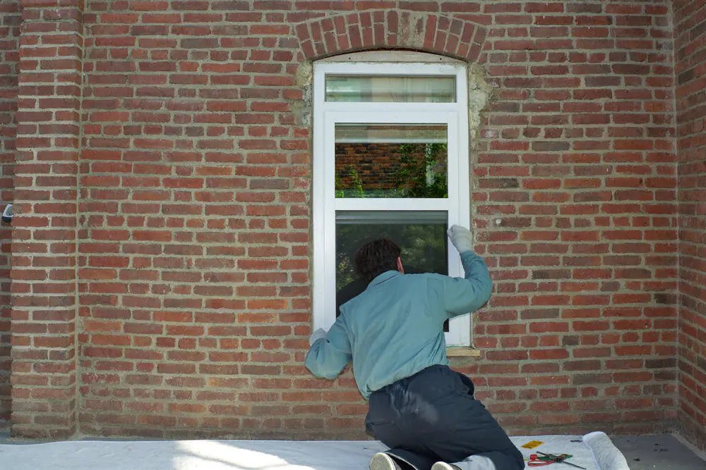 Monteur plaatst een nieuw kunststof renovatiekozijn in de opening van een oud kozijn