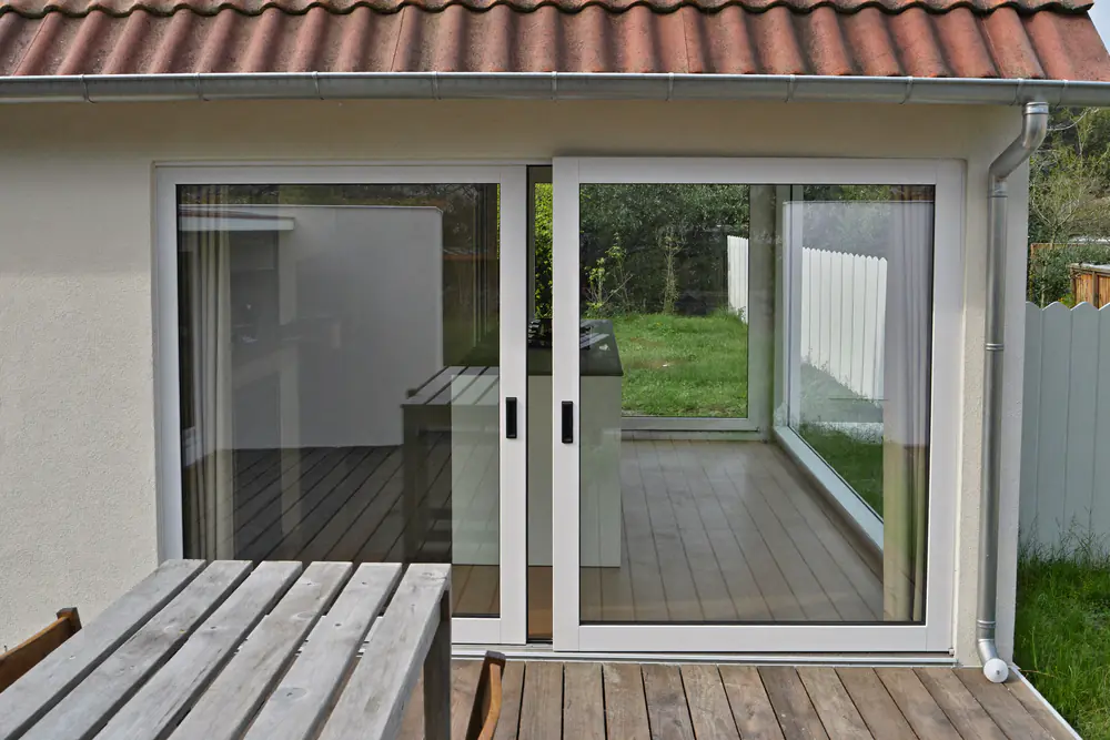 Nieuwe witte schuifpui achter in een rijtjeshuis met zicht op de tuin en het terras